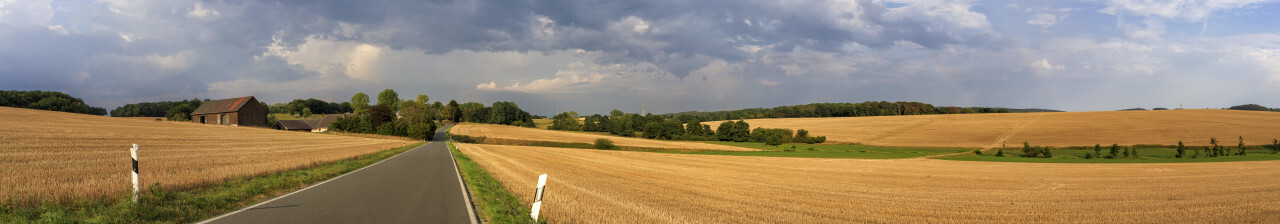 Stormy clouds are gathering over a rural landscape with a Farm and a country road between fields in Germany near Velbert Langenberg, Neviges in North Rhine Westphalia