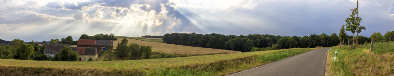 Thunderstorm clouds are gathering over a rural landscape with a Farm and a country road between fields in Germany near Velbert Langenberg, Neviges in North Rhine Westphalia