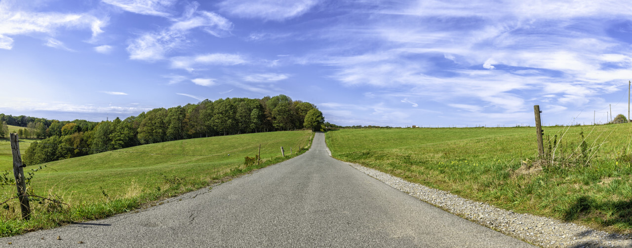 country road through rural landscape with field and blue sky, wuppertal ronsdorf, nrw germany