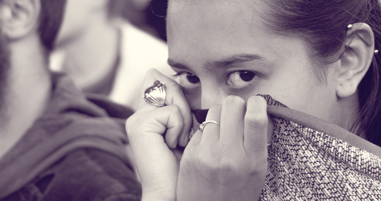 woman hides her face with the collar of her sweater