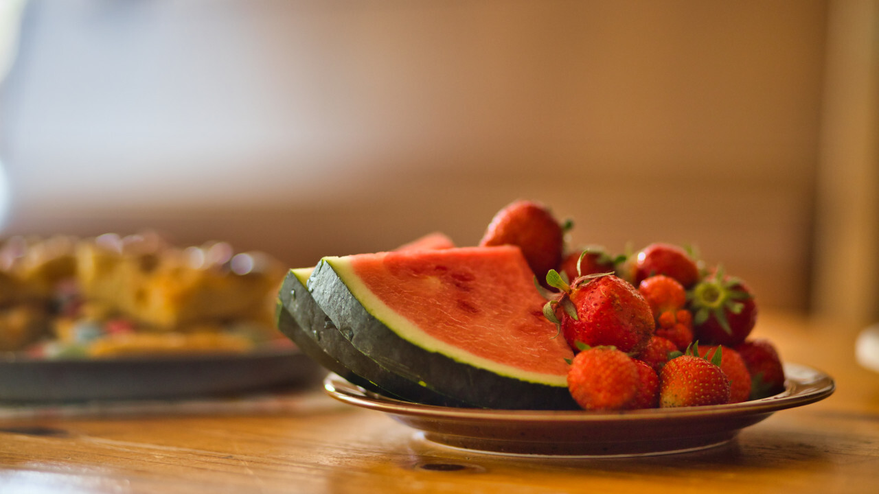 A plate of watermelon slices and fresh strawberries