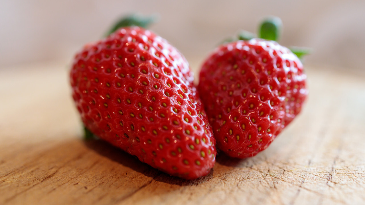 Two strawberries on a wooden board