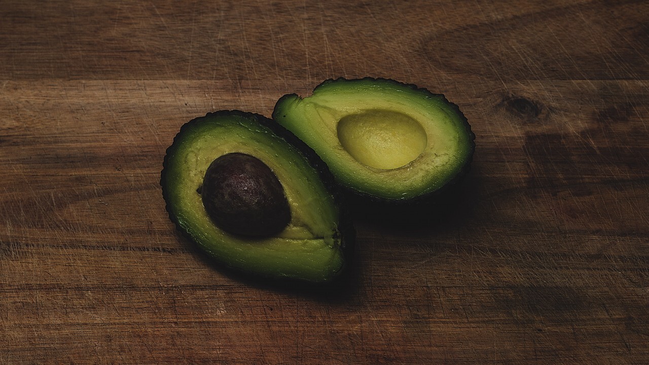 Food background with fresh organic avocado on old wooden table