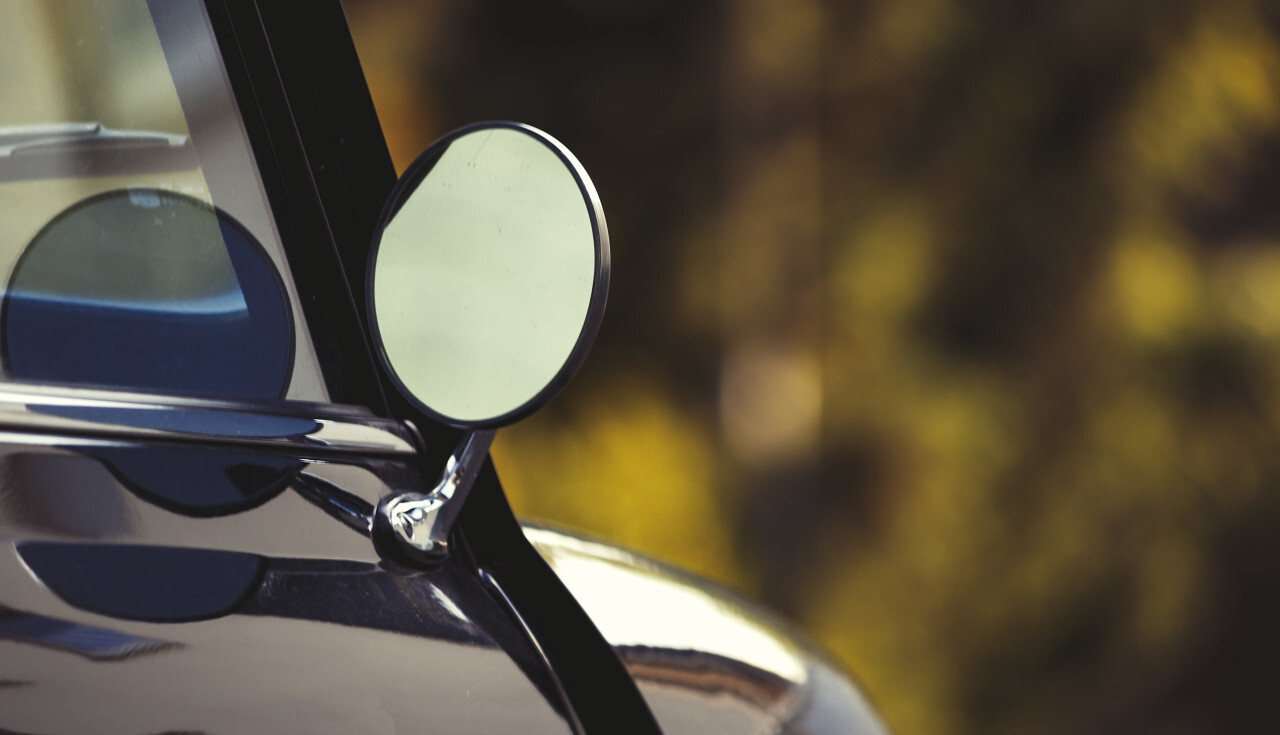 Side rear-view mirror and reflection in the window on black retro car