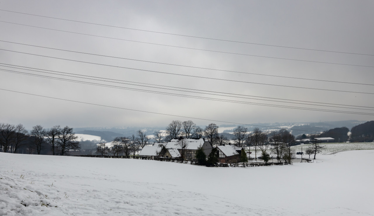 German snow landscape in winter with a snow-covered farm in the foreground