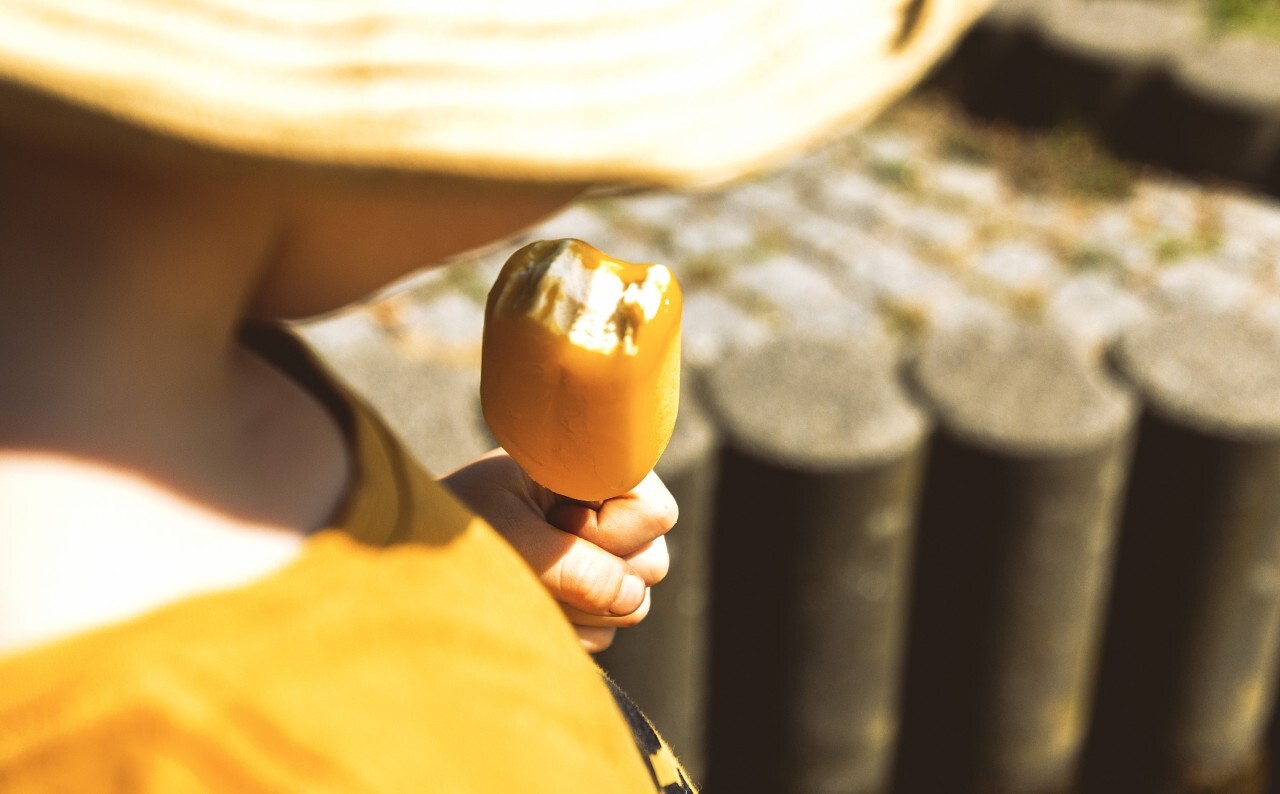 children eats yellow maracuja ice lolly