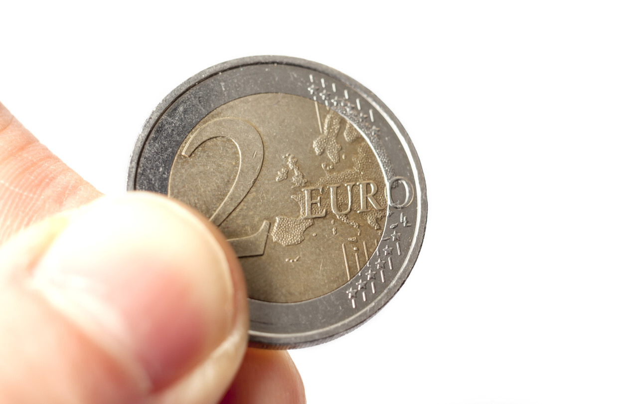 Hand holding two euro isolated on white background