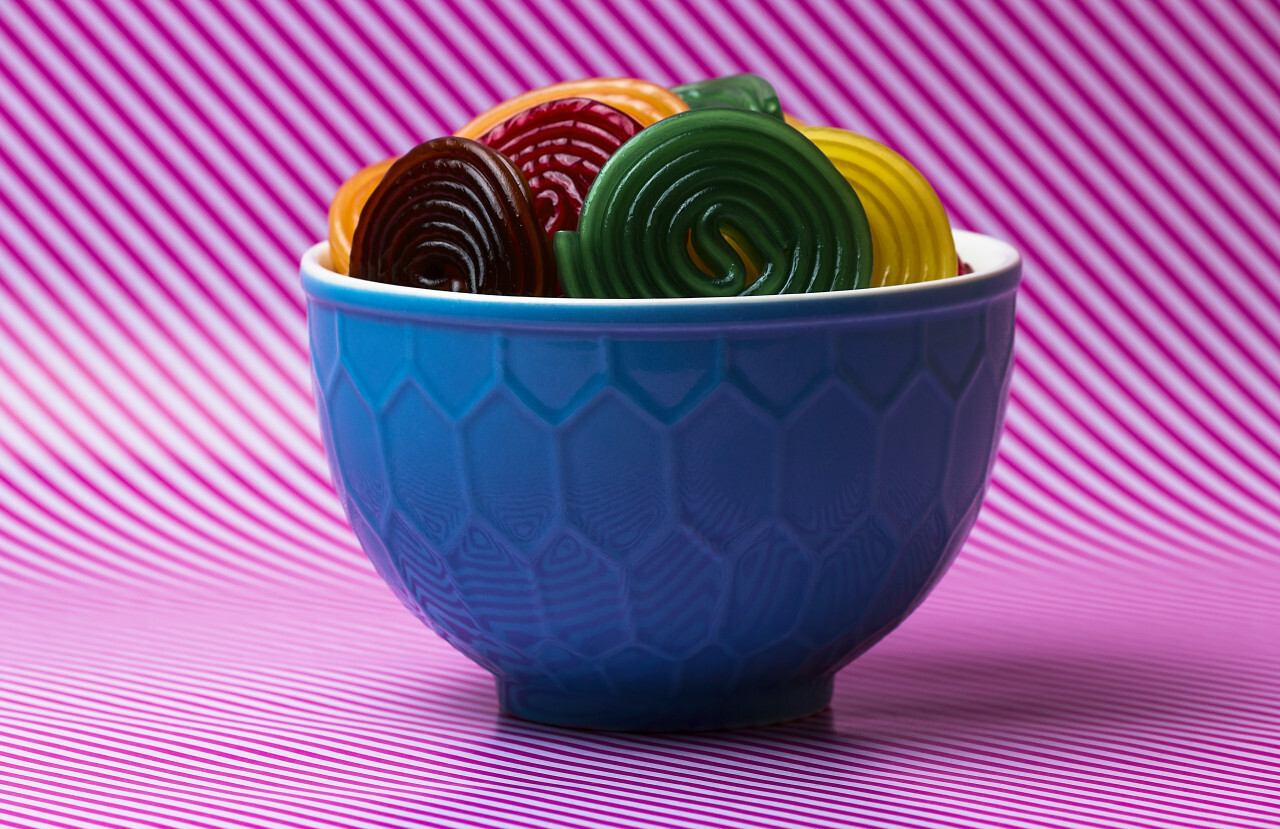 colorful sugar snails in a bowl on a pink and white striped background