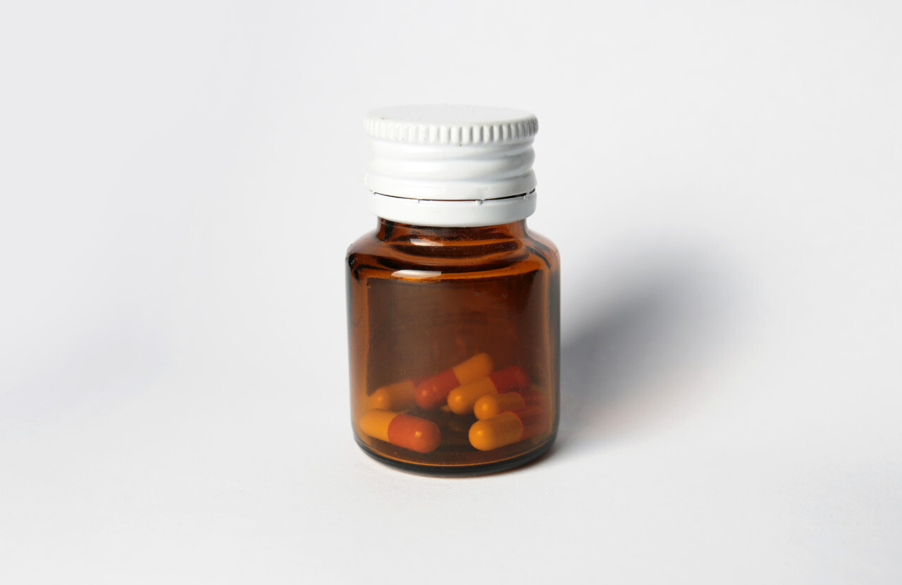 Brown glass bottle with vitamin or supplement product and white cap