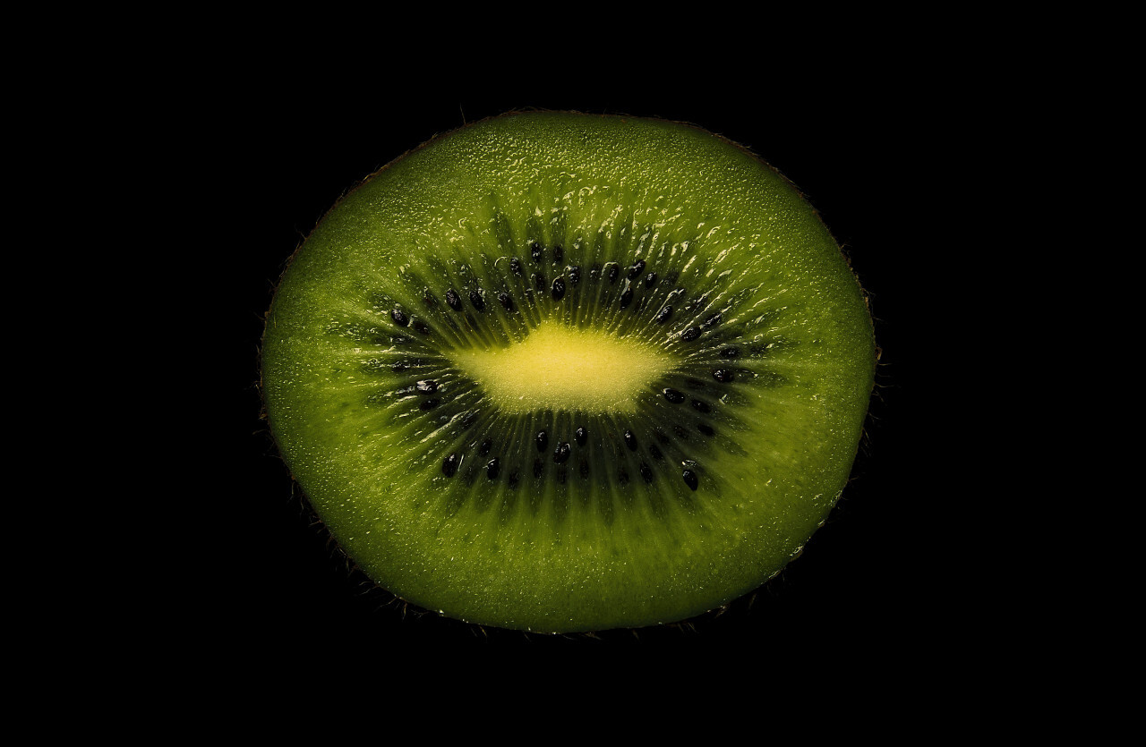 Slice of a kiwi fruit on a black background