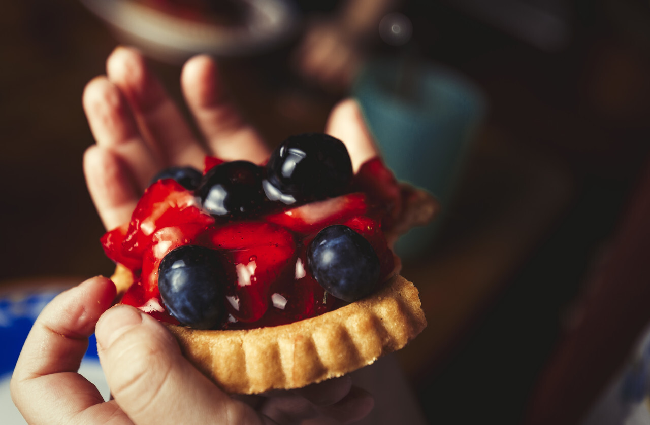 Sweet tart with berries in a hand of children