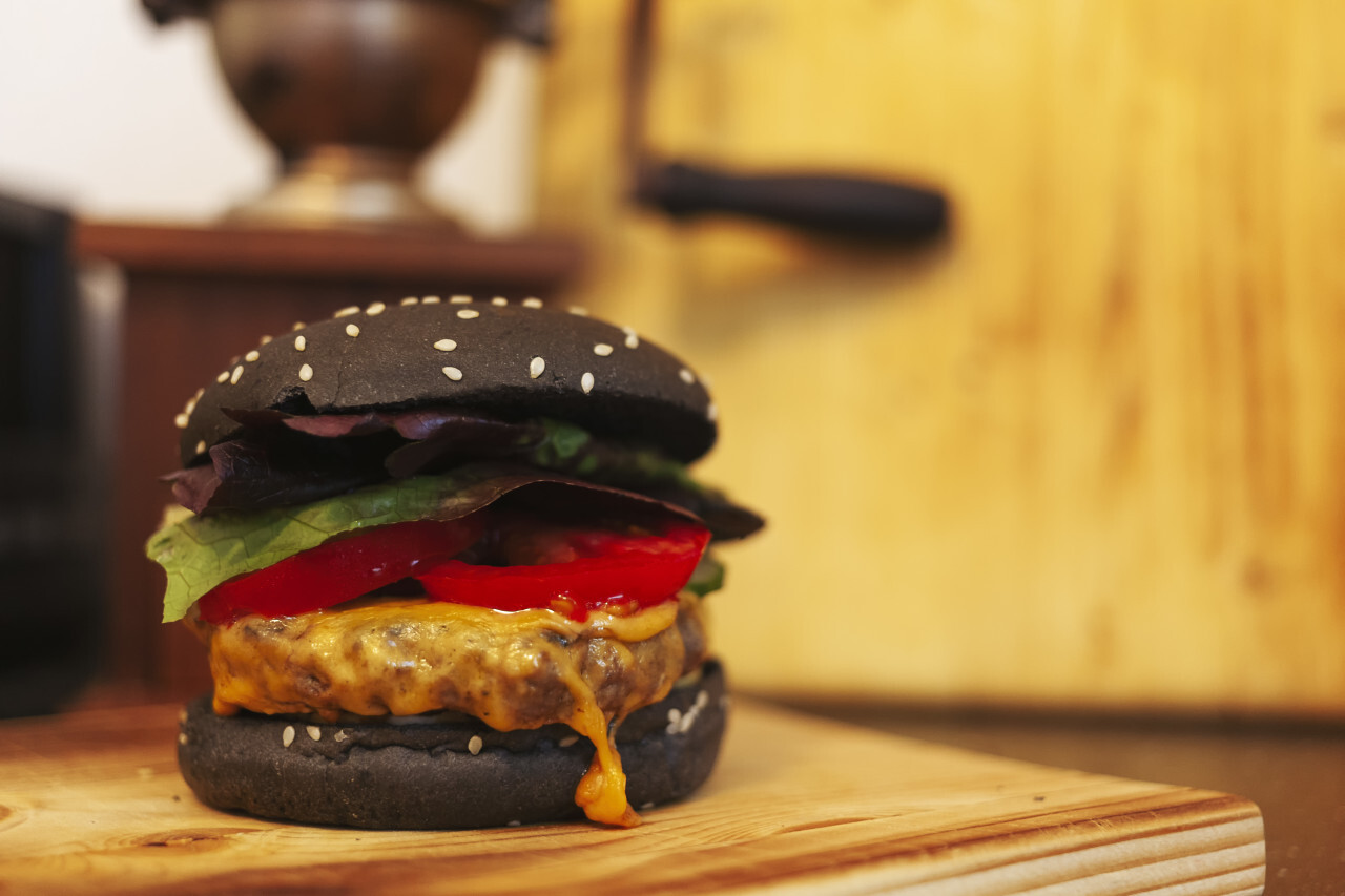 black hamburger on a wooden plate