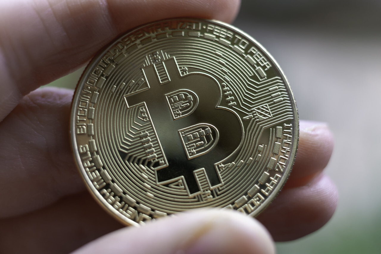 Golden Bitcoin between human fingers