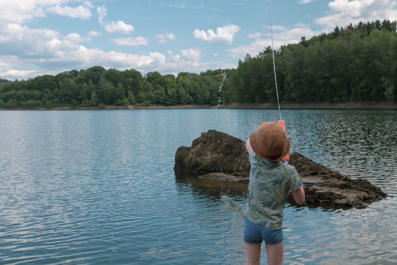 child is playing with a watergun on a lake  - landscape in germany nrw wuppertalsperre