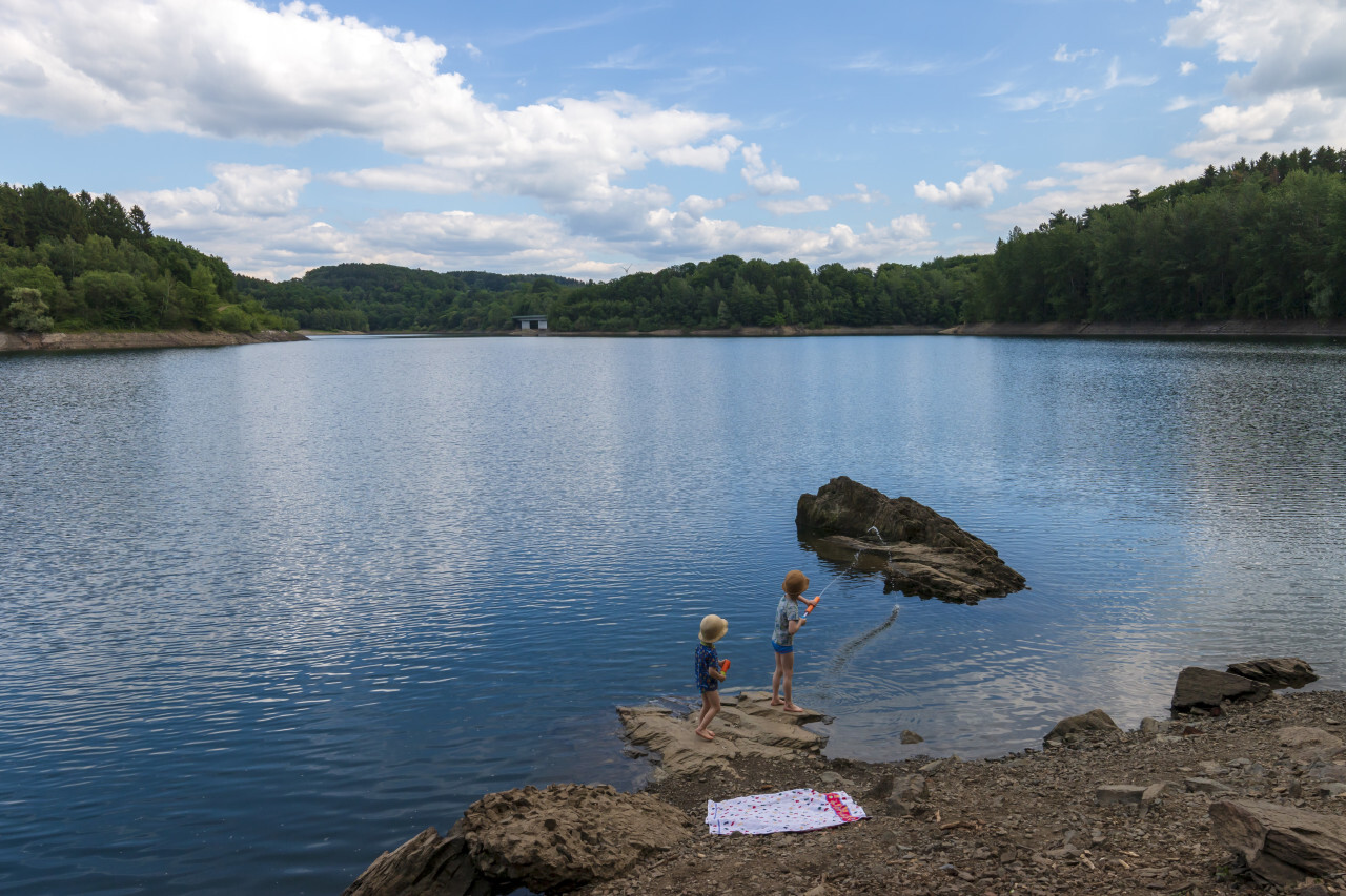 children playing with water guns on a lake - landscape in germany nrw wuppertalsperre