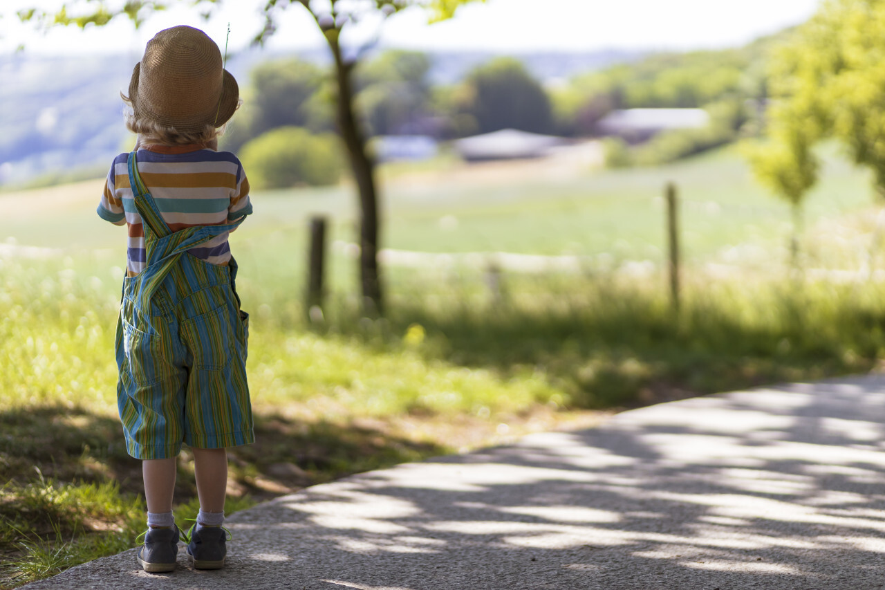 Little boy with a hat looks at the rural landscape in germany