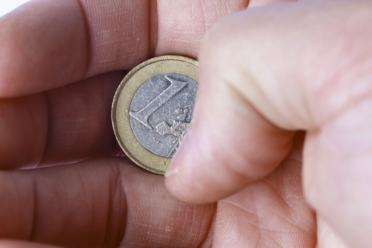One euro coin in a hand isolated on a white background