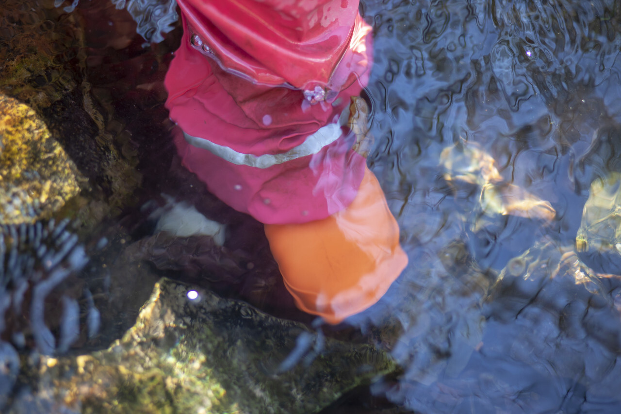 Child with rubber boots standing in a stream