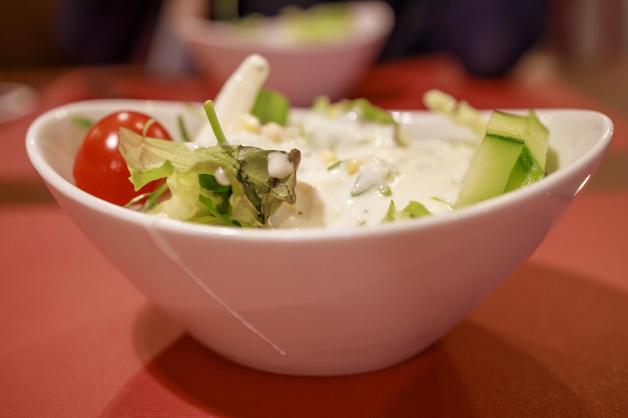 Simple salad in a white bowl in a restaurant as a starter