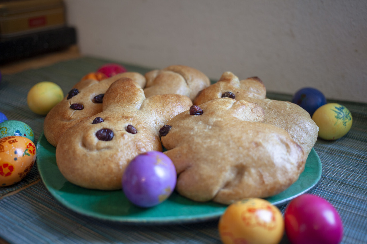 Plate with bread in an Easter bunny shape with easter eggs arround it