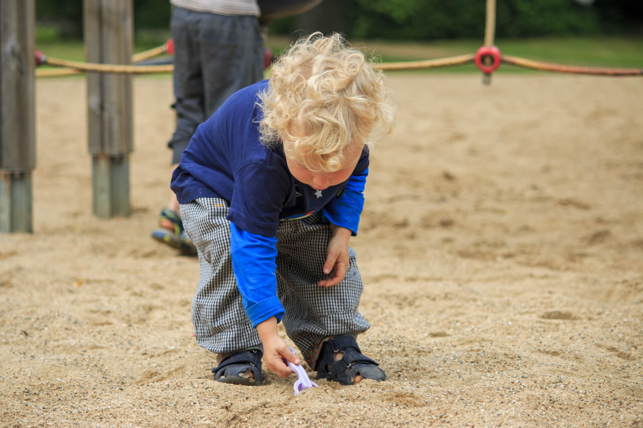 toddler is playing in the sandbox