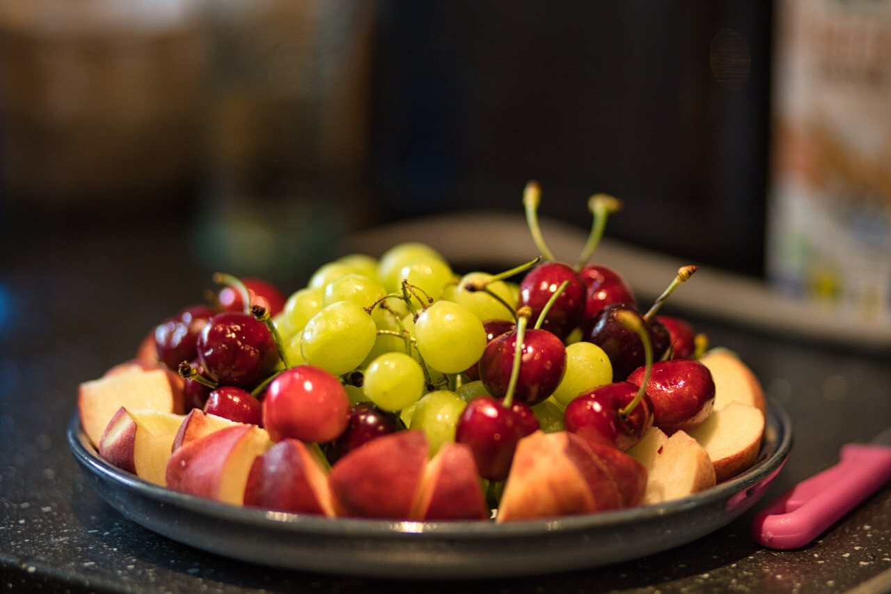 Plate in the kitchen filled with cherries, grapes and pieces of peach