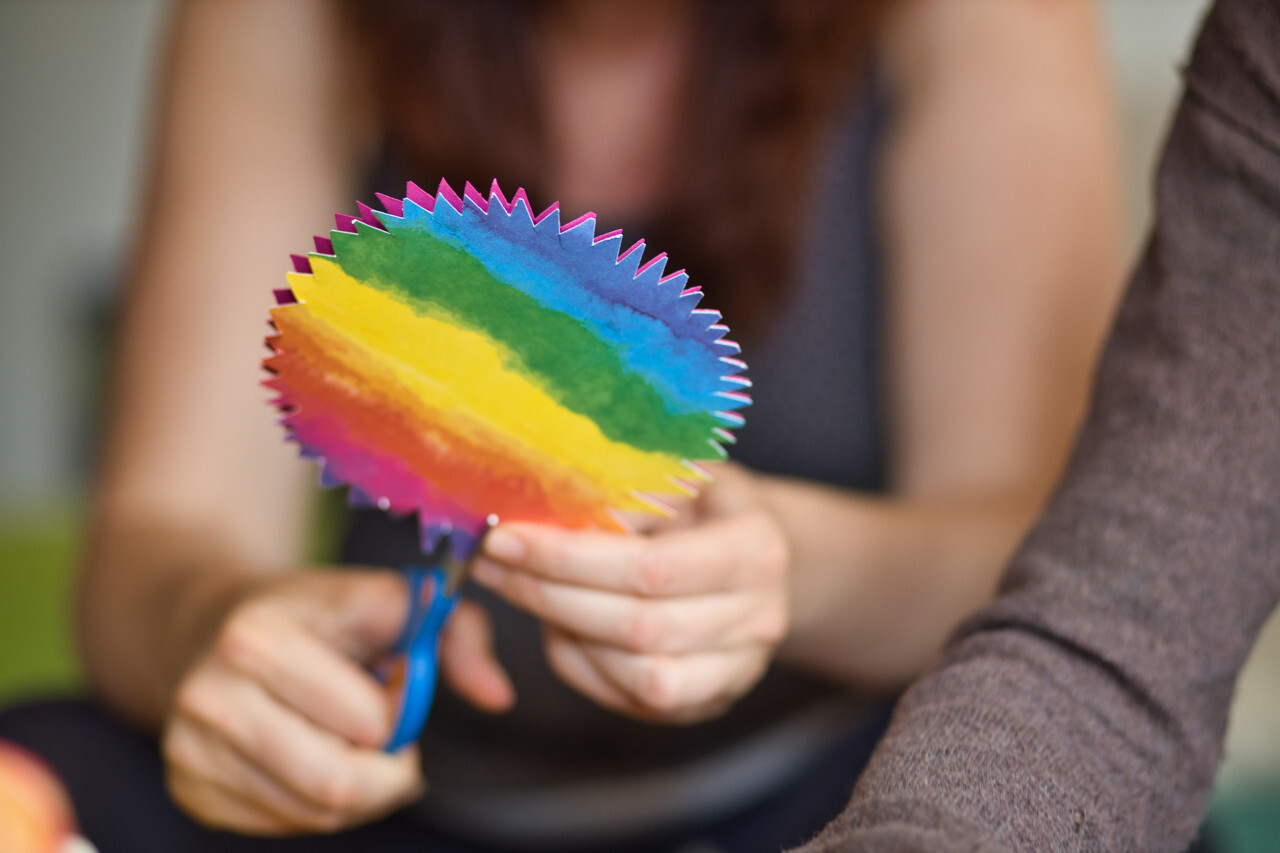 Woman cut out rainbow colored paper in a circle