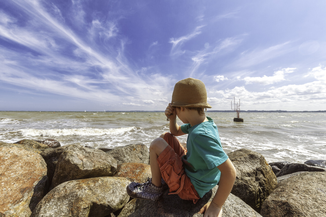 child on rocks looks on the baltic sea