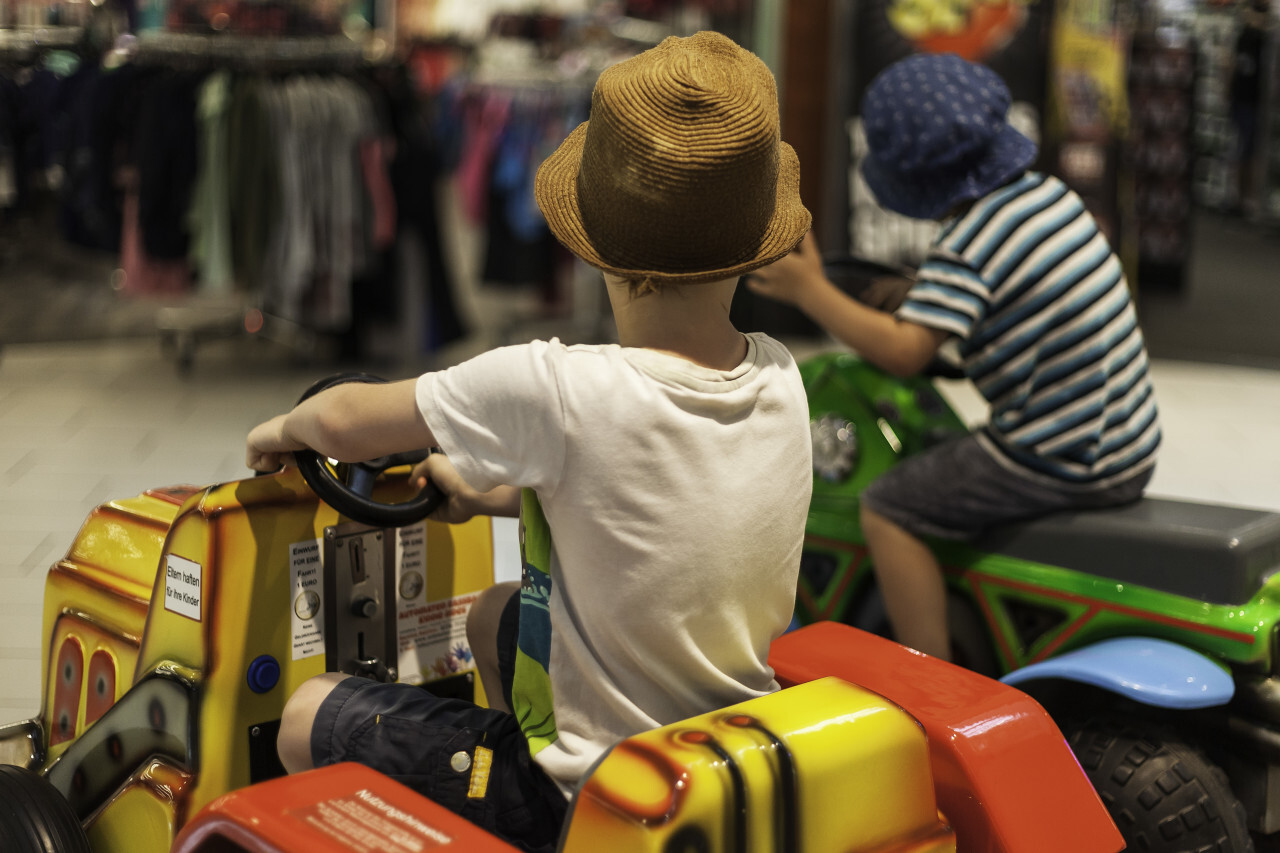 children in the department store on a vending machine carousel