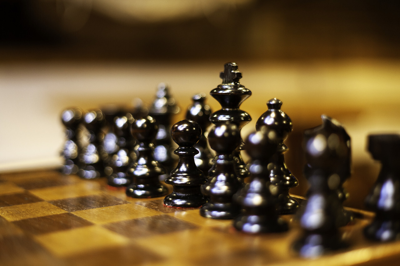 selective focus of wooden chessboard with black chess figures