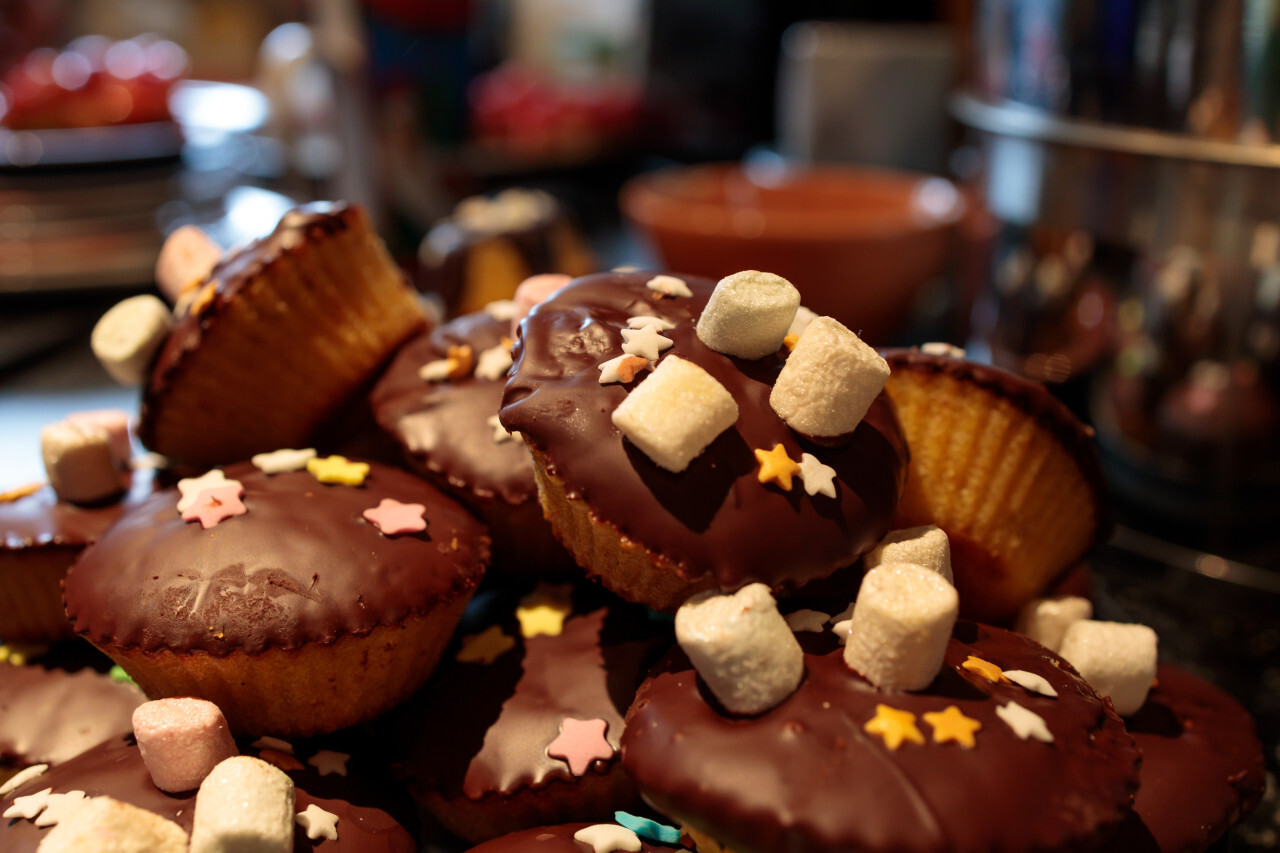 Small chocolate muffins decorated with colored sugar stars and marshmallows