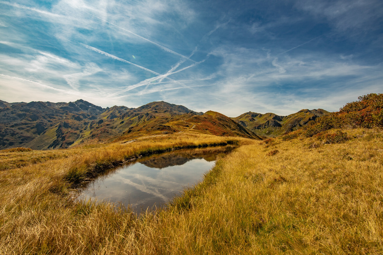 Landscape panorama of the Austrian Alps with a small waterhole