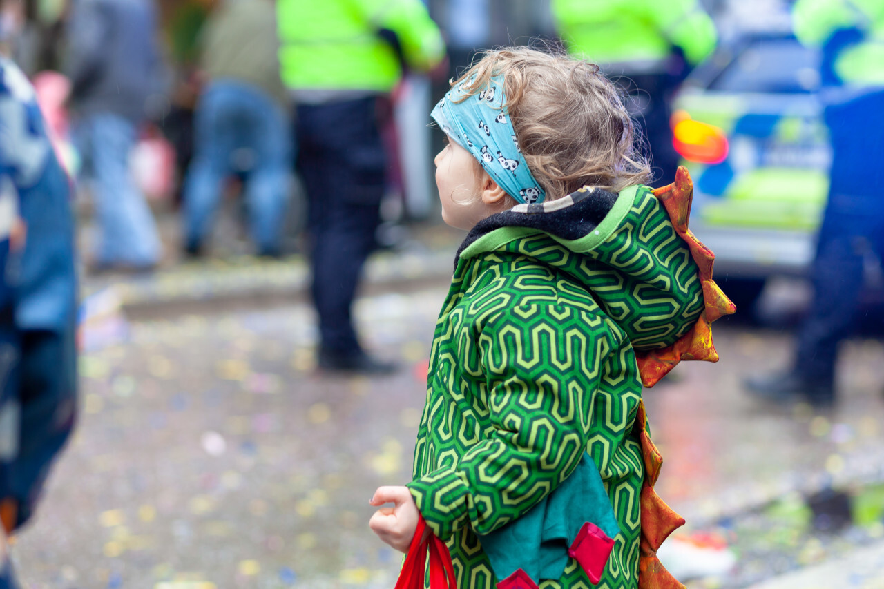 Toddler in dragon costume is waiting eagerly for the carnival parade