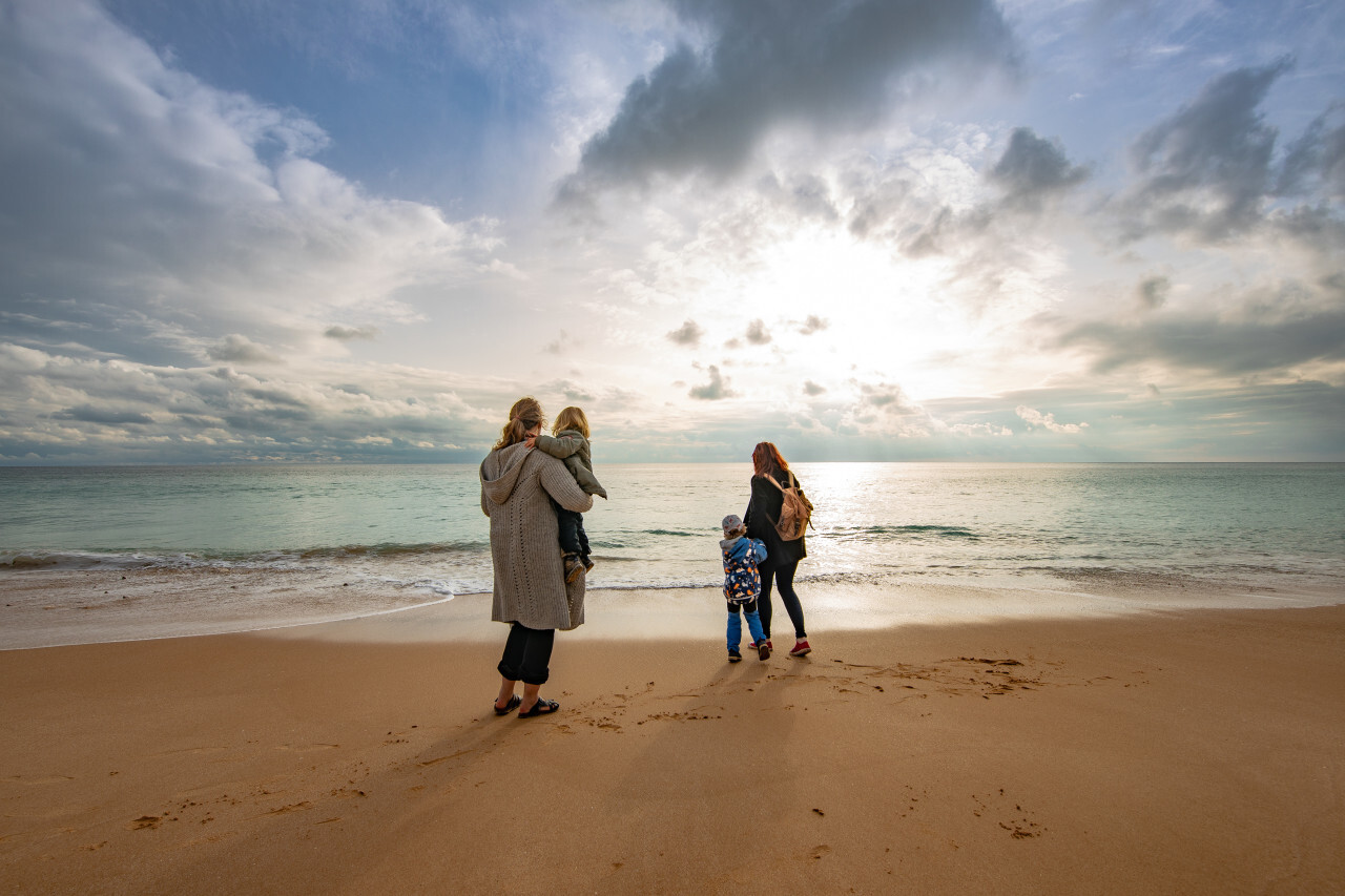 Family with children on the beach in Portugal look into the distance of the sea