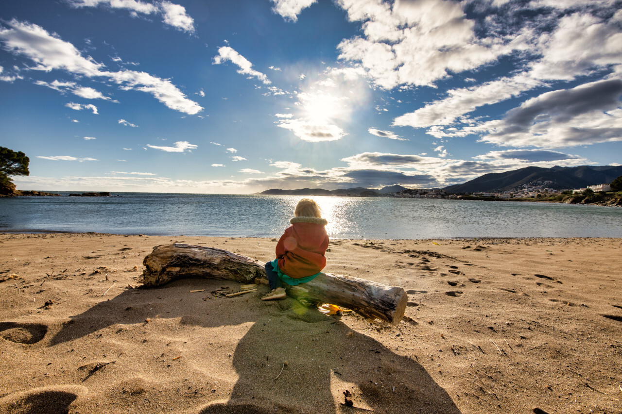 Girl sitting on the beach of Platja Grifeu by Girona in spain