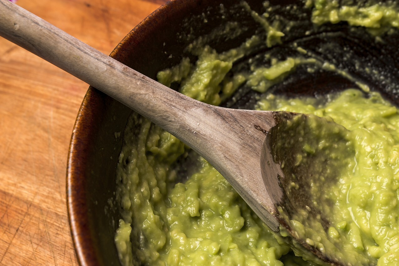 guacamole in bowl with wooden spoon