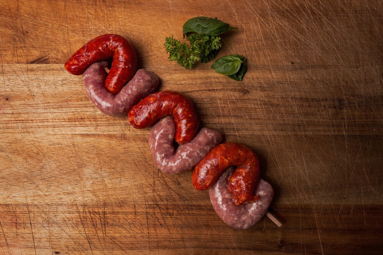 raw german sausages skewer on a wooden board