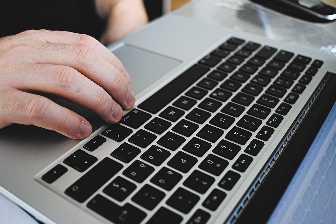 Closeup male hands typing on notebook keyboard at home office. Man using laptop