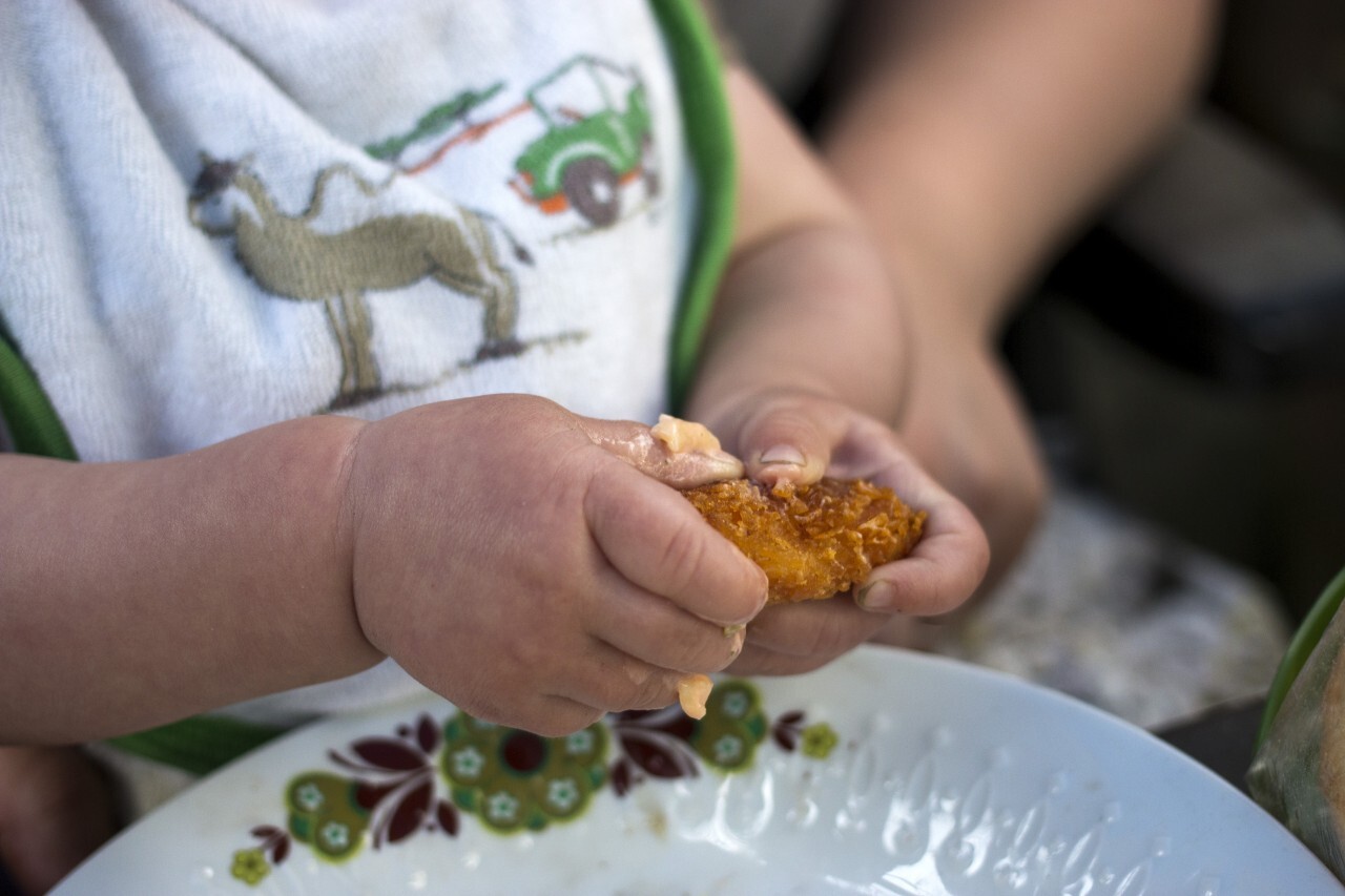 Baby girl eating a chicken wing