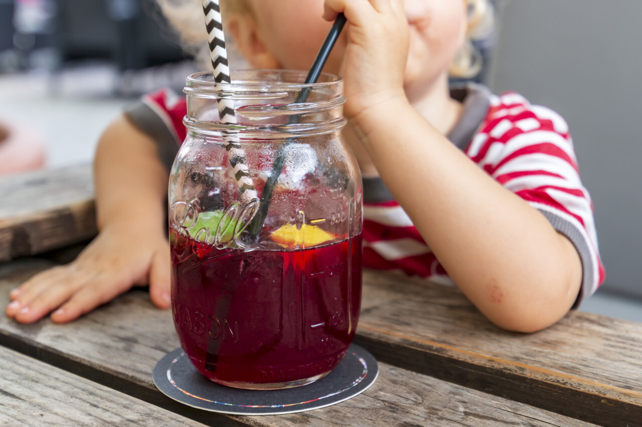 Little Child drink juice or ice tea or summer drink from glasses through straws