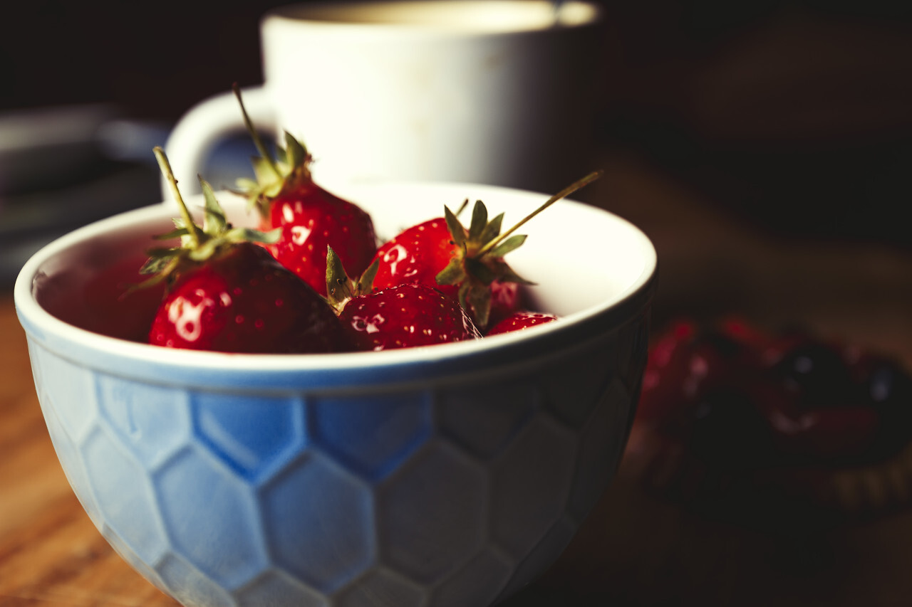 blue bowl of strawberries with coffee and cake