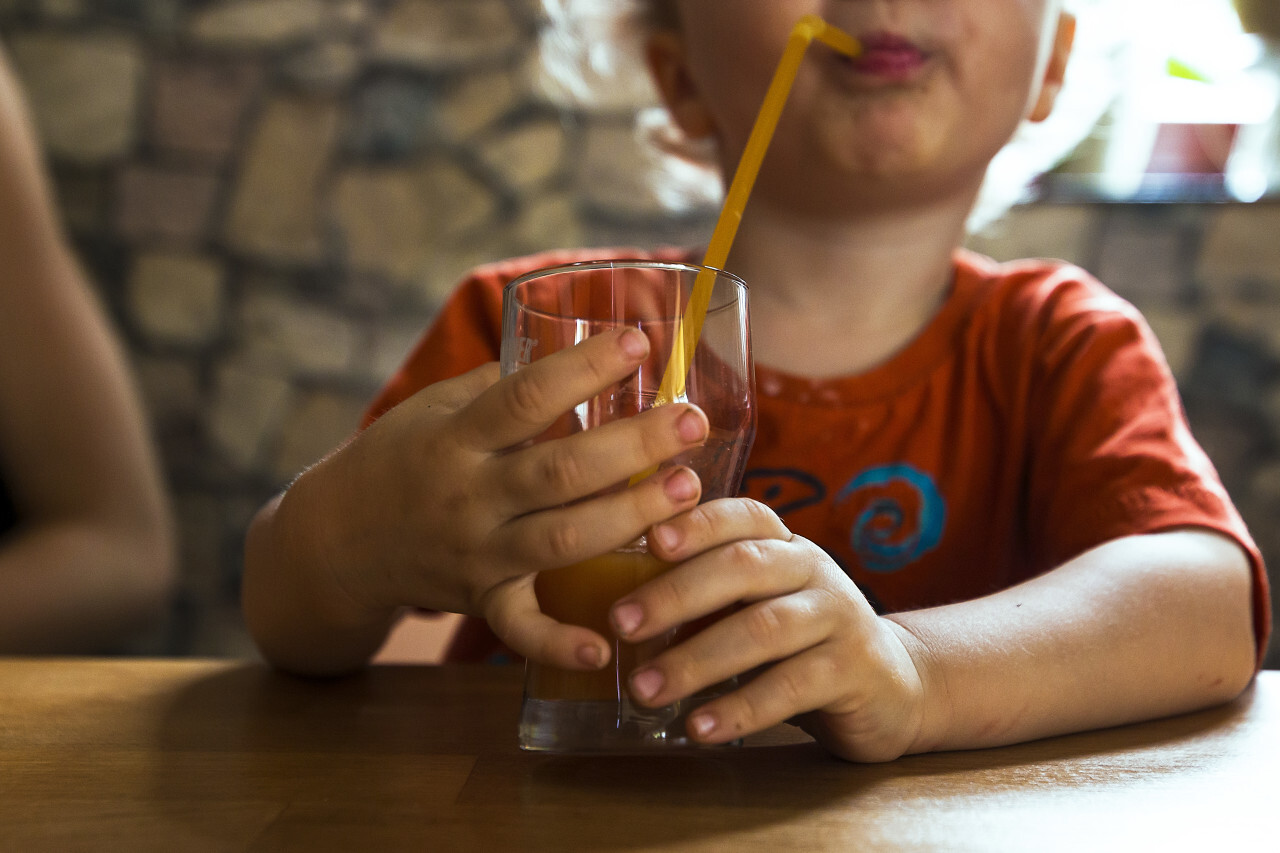 child drinks juice with straw