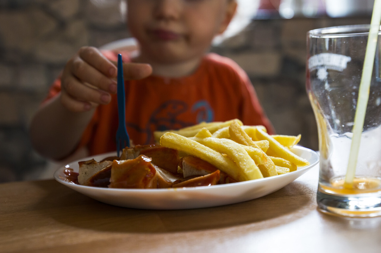 child eats currywurst with french fries