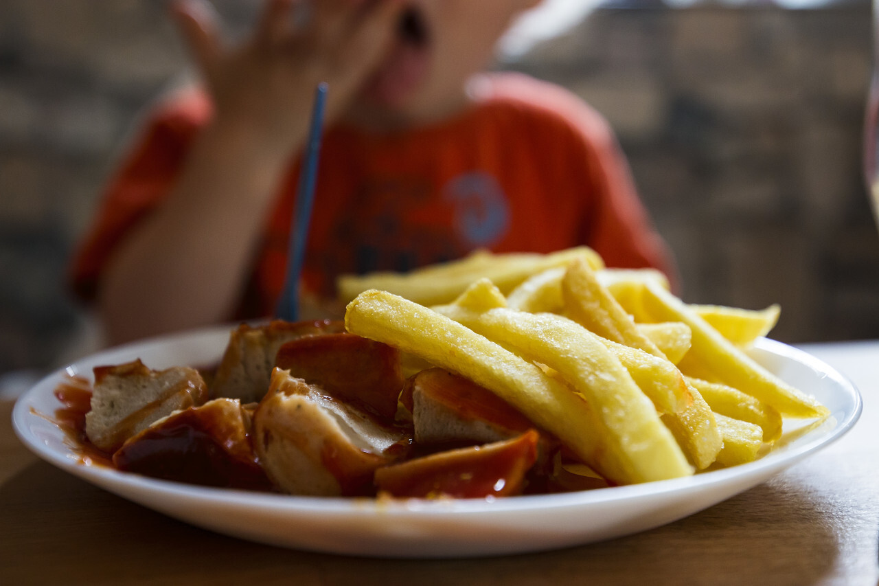 child eats currywurst with french fries