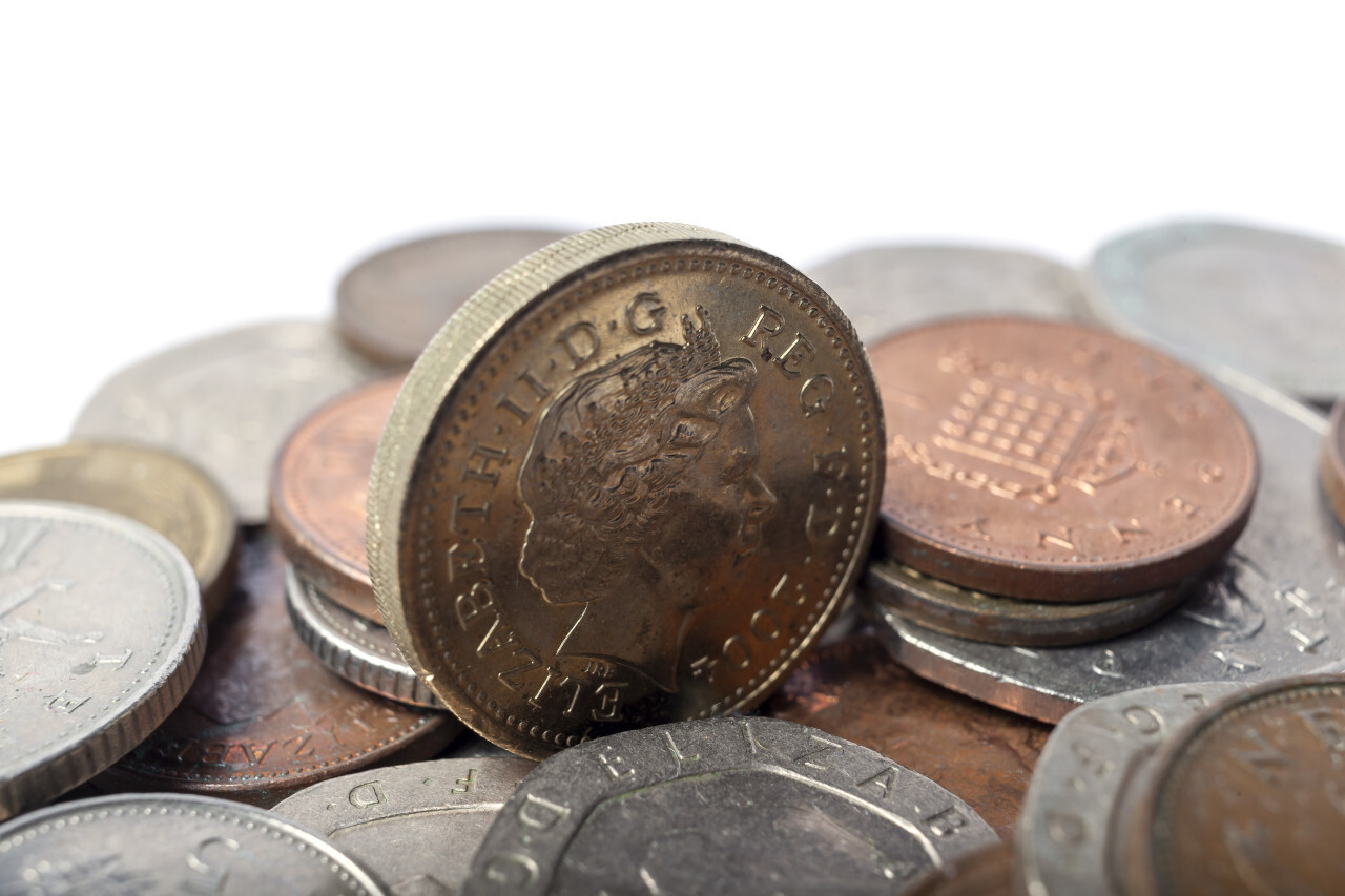 One british pound coin and a stack of small change isolated on white background