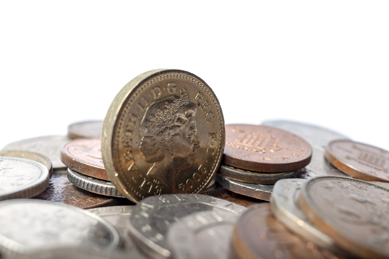 One british pound coin and a stack of small change isolated on white background