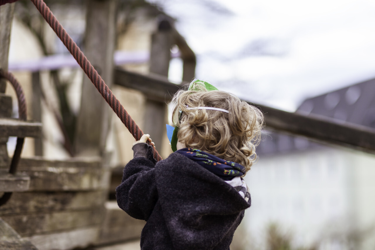 Little boy climbs on a rope in a playground