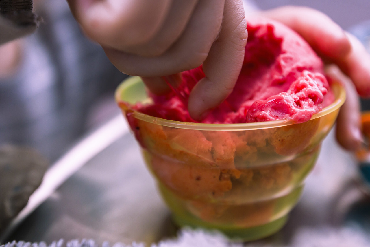 childs hand on strawberry ice cream cup