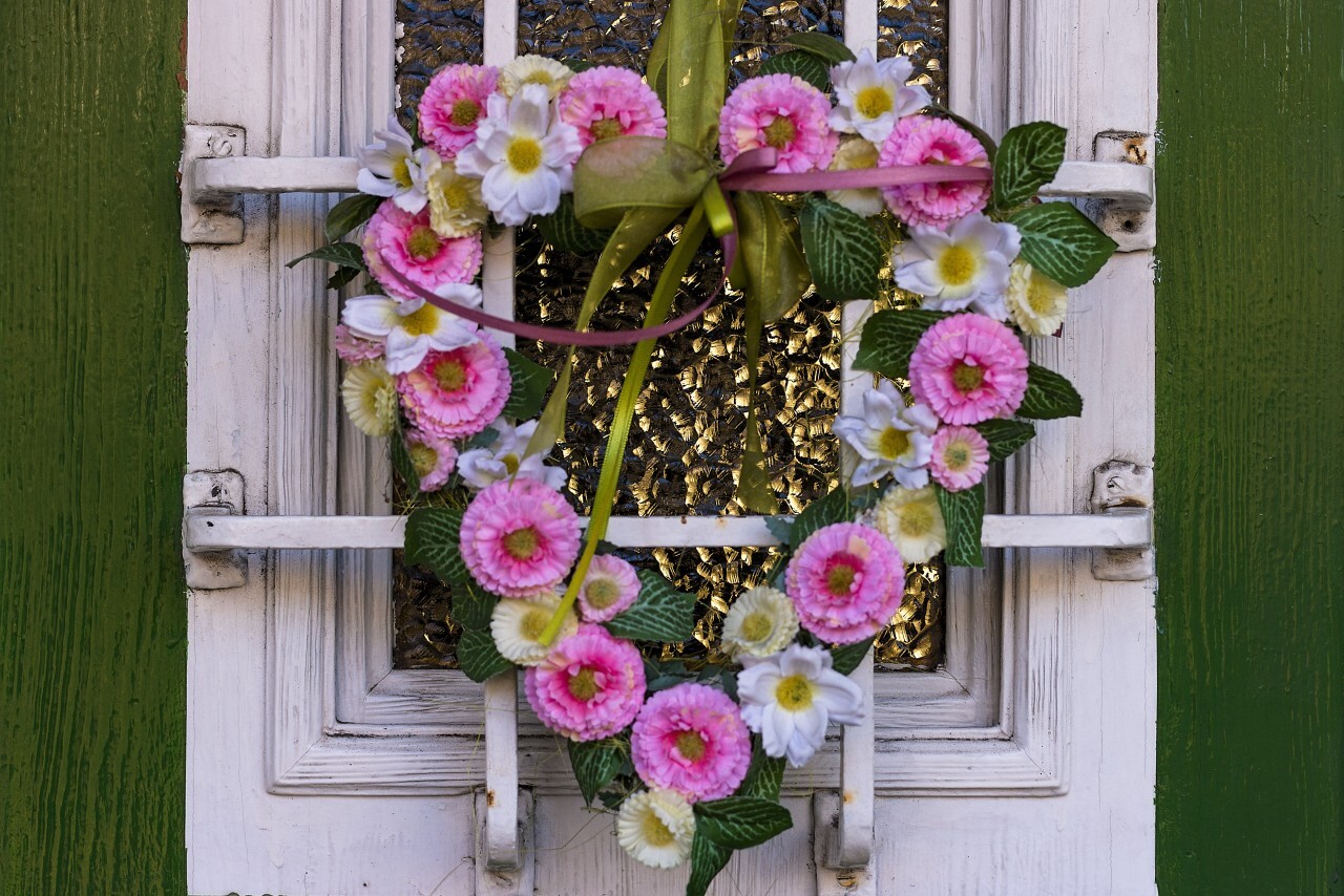 Handmade spring flower wreath on rustic wooden door with velvet material