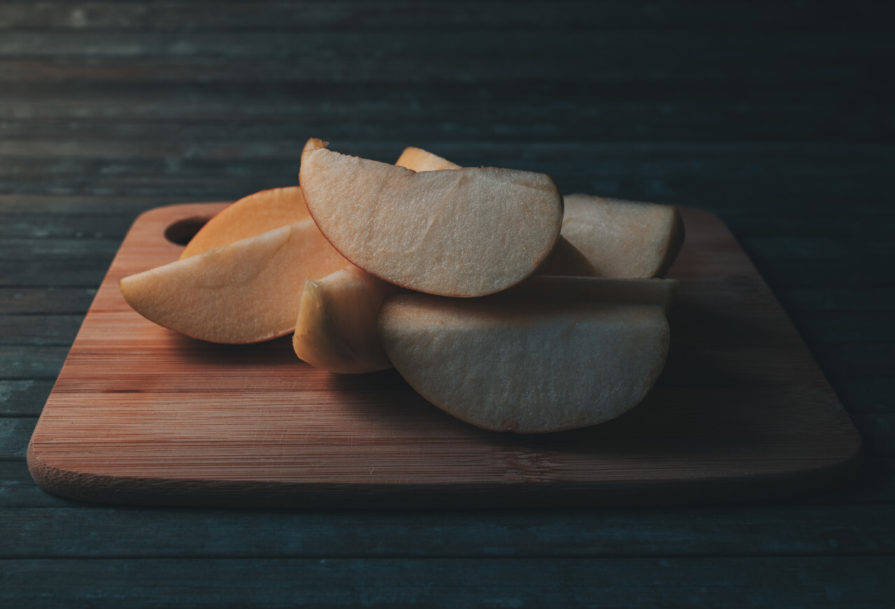 Thin apple slices in a kitchen on a wooden board